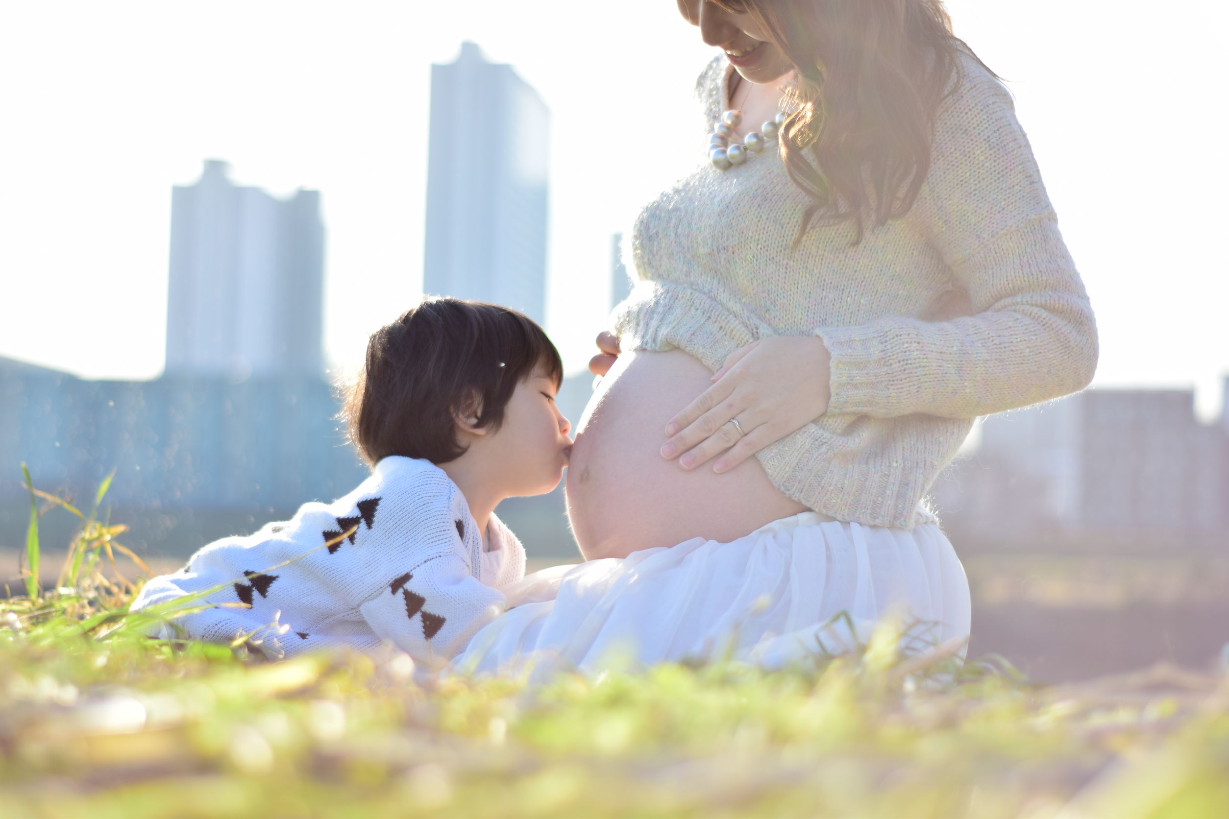 照片：一個小孩正在吻一位懷孕女性的肚子